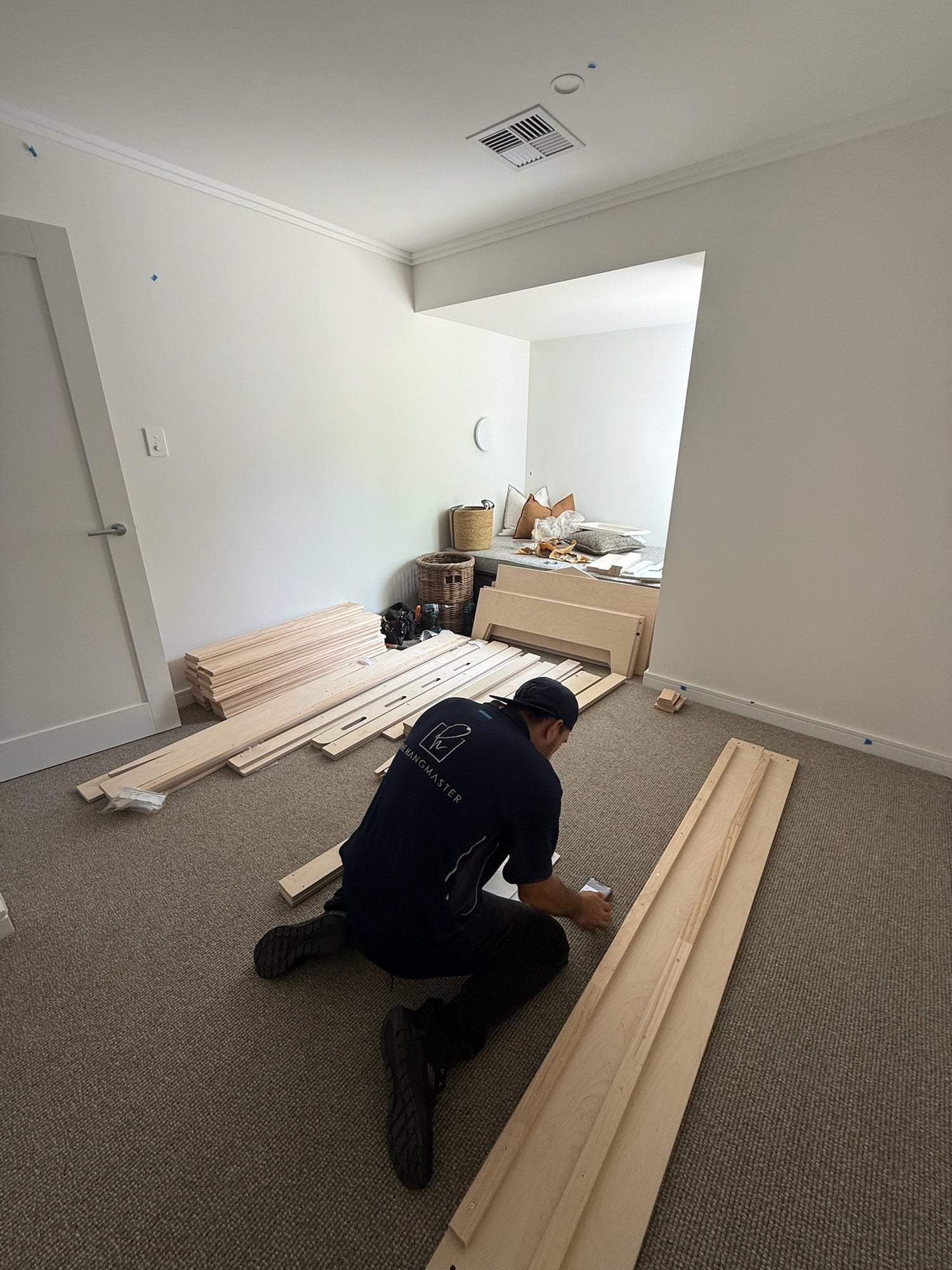 A Hangmaster worker is working with wooden planks for wall mounting.