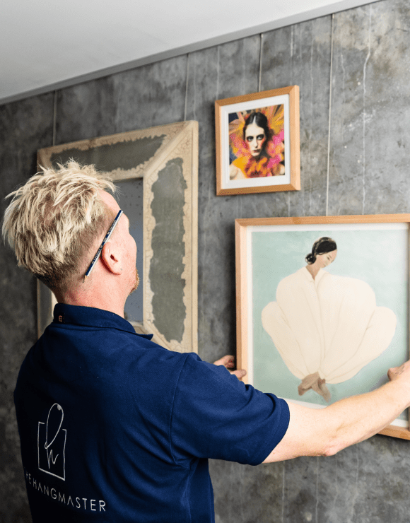 hanging a framed artwork on a wall.
